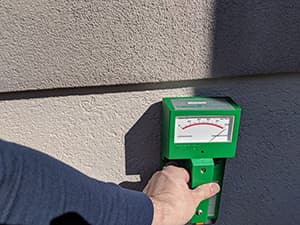 EIFS Inspection moisture scan device held up to the outer wall of a home.